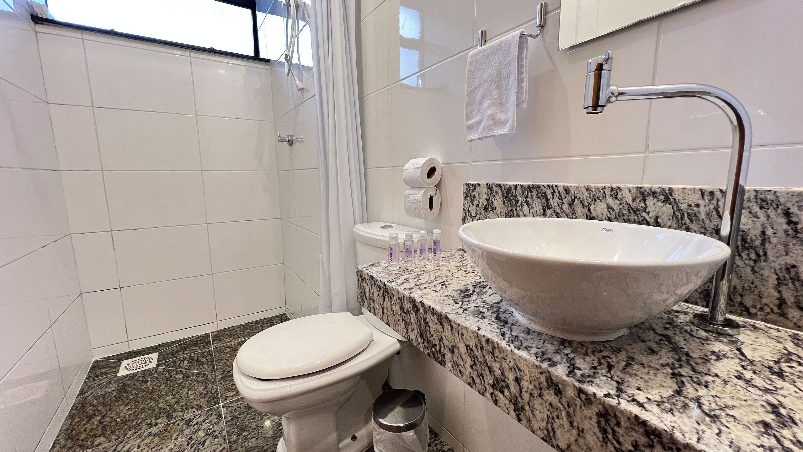 Casa de banho com sanita, lavatório e chuveiro.