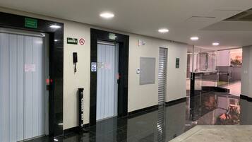 A clean, well-lit hallway with a polished floor, an elevator, and a door marked 'GARAGEM 3'.
