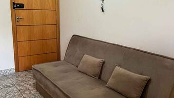 Ein Zimmer mit Holztür, einer Couch, einem Wandtelefon und einem Fliesenboden.