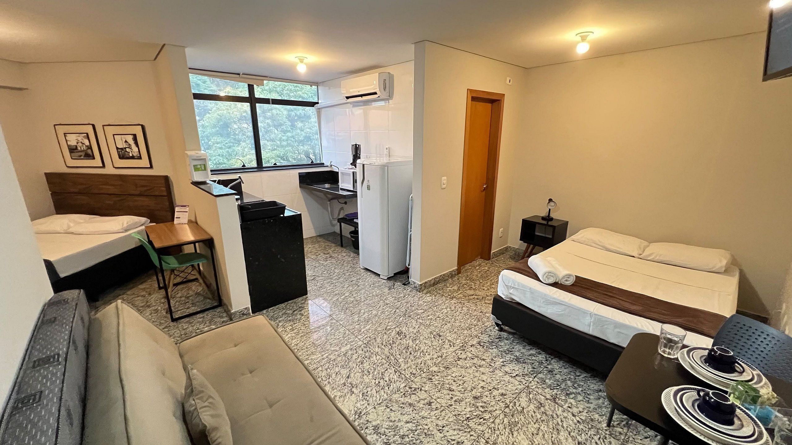 Un espacio habitable compacto con kitchenette, cama, sofá y zona de comedor.