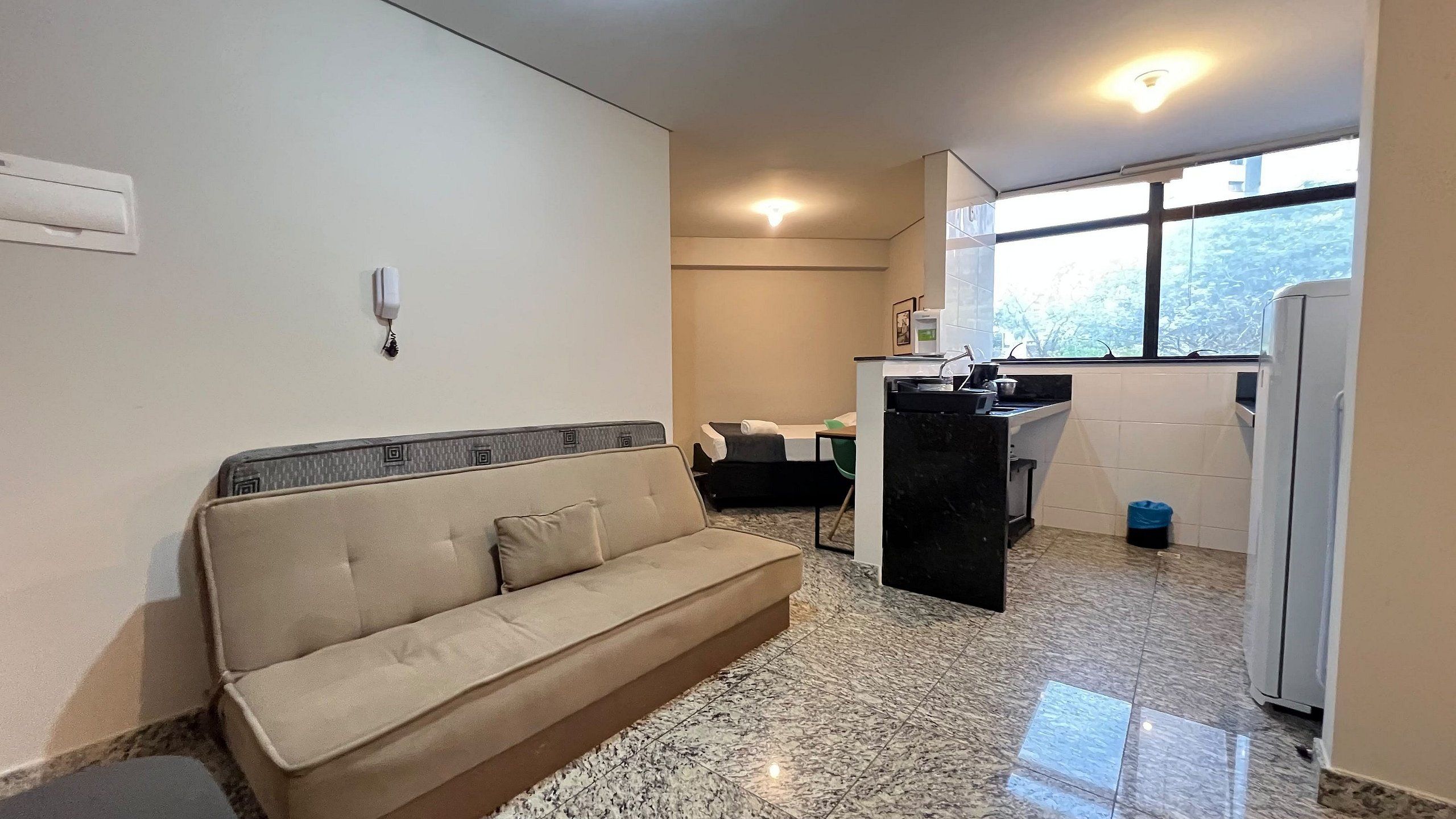 Un espacio habitable compacto con sofá, kitchenette y ventana que proporciona luz natural.