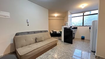 Un espacio habitable compacto con sofá, kitchenette y ventana que proporciona luz natural.