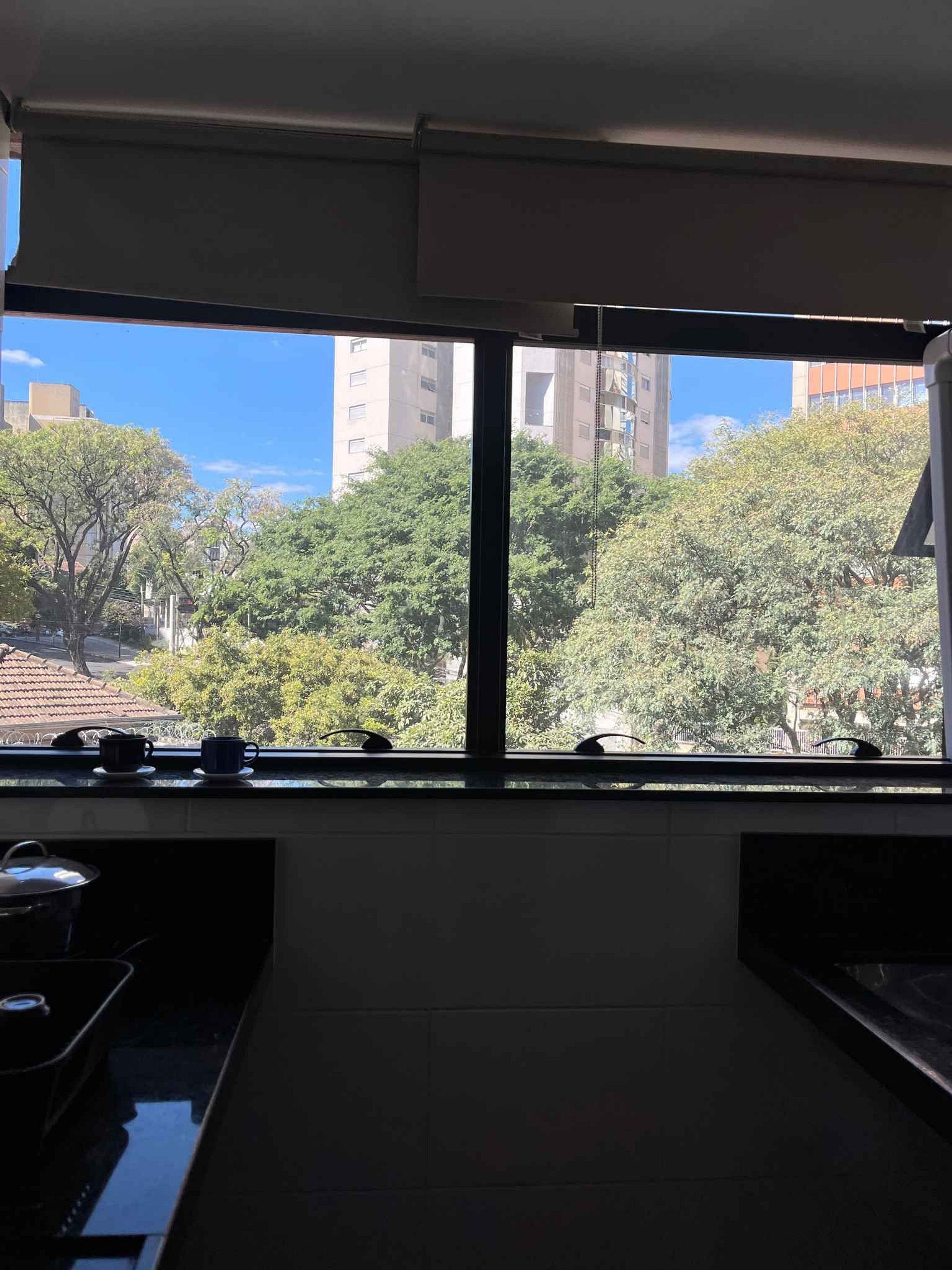 Una cocina con un ventanal amplio que da a una vista urbana, una estufa y un lavamanos.