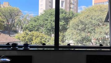 Una cocina con un ventanal amplio que da a una vista urbana, una estufa y un lavamanos.