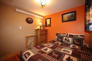 Un dormitorio con cama, cómoda y una lámpara fijada a la pared.