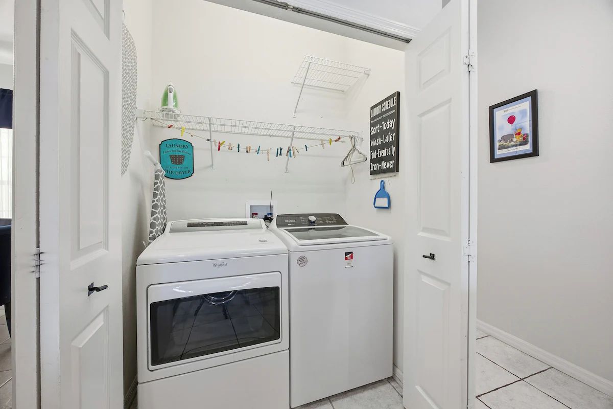 Un espace dédié à la buanderie, équipé d’un lave-linge et d’un sèche-linge, d’un étendoir et d’un tableau indiquant le planning de lessive.