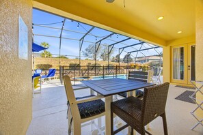 A covered patio with a pool, outdoor seating, and a view of the surrounding landscape. - Dreamers Retreat! Spacious Disney-Area Pool Home for Families & Adult Getaways (Kissimmee)