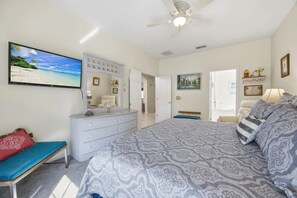A bedroom with a bed, dresser, and a TV displaying a beach scene. - Dreamers Retreat! Spacious Disney-Area Pool Home for Families & Adult Getaways (Kissimmee)