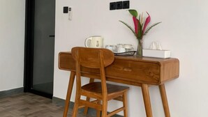 A wooden desk with a chair, a vase with flowers, and a small tray with items. - Cozzy Sagas  House Tabanan (Marga)