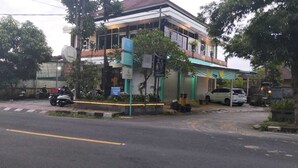 A building with a sign indicating a business establishment, a parked motorcycle, and a car on the street. - Cozzy Sagas  House Tabanan (Marga)