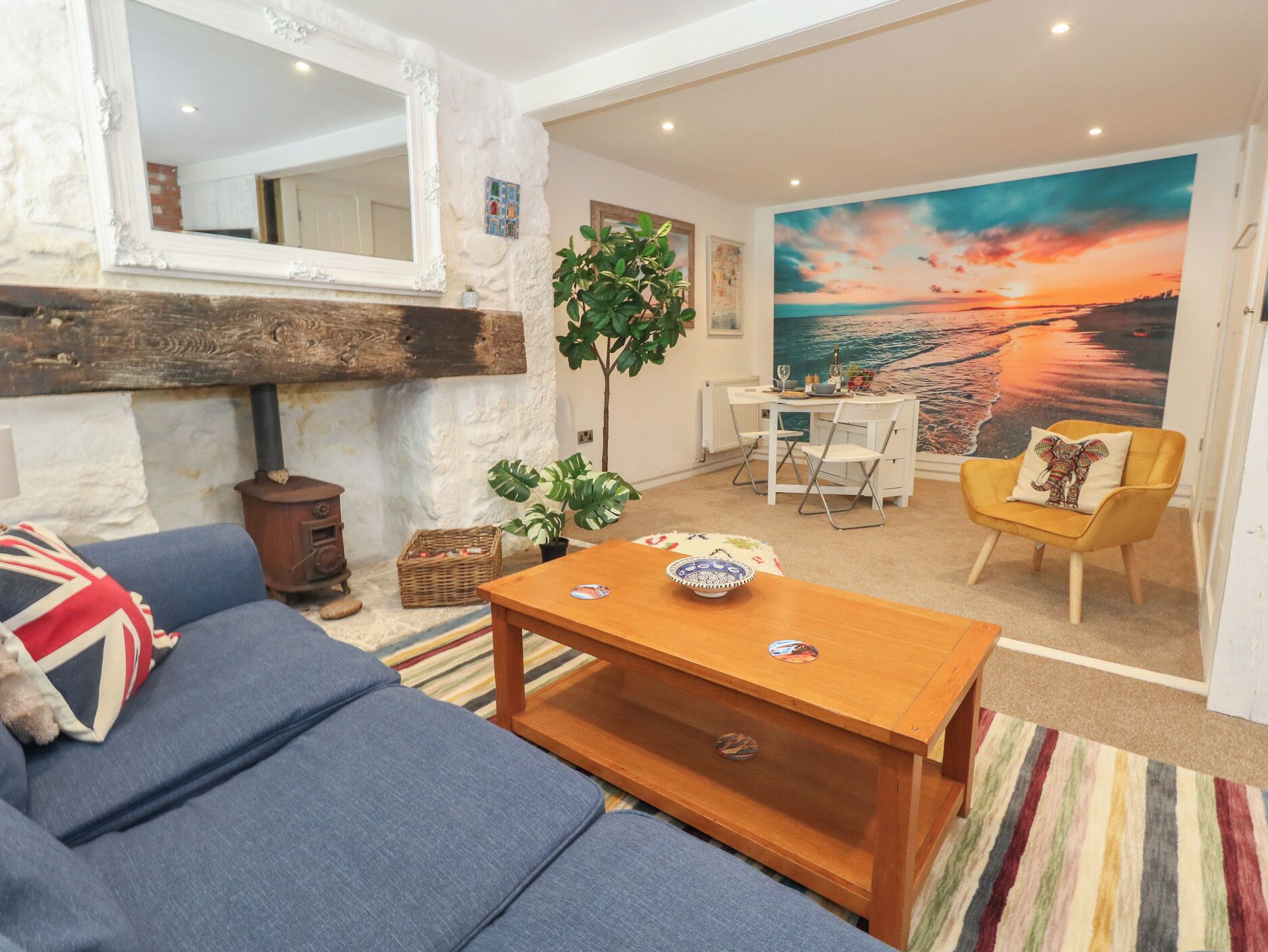Una sala de estar con sofá, mesa de centro y un cuadro de un atardecer.