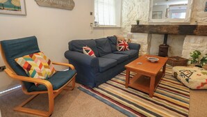 A living room with a sofa, a chair, a coffee table, a fireplace, and a 'Be our guest' sign. - Tipsy Turtle (Portland)