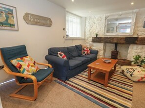 A living room with a sofa, a chair, a coffee table, a fireplace, and a 'Be our guest' sign. - Tipsy Turtle (Portland)