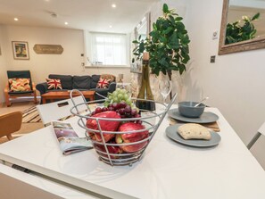A dining area with a table set for two, featuring a fruit basket, a bottle of wine, and a bowl of bread. - Tipsy Turtle (Portland)