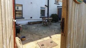 A courtyard with a wooden table and chairs, a metal manhole cover, and a small bush. - Tipsy Turtle (Portland)