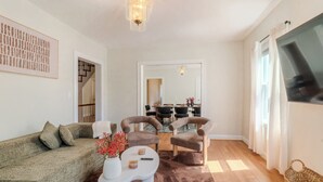 Een woonkamer met een bank, twee fauteuils, een salontafel en een eethoek op de achtergrond.
