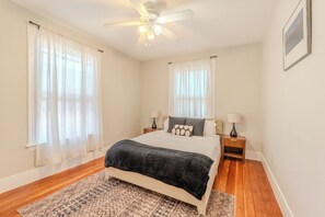 A bedroom with a bed, two bedside tables, a ceiling fan, and a window with sheer curtains. - Lovely 10-bedroom, 14 bed house in tranquil Somerville perfect for groups (Somerville)