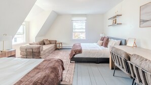 Een slaapkamer met een loft-plafond, een bed, een bank, een bureau en een stoel.