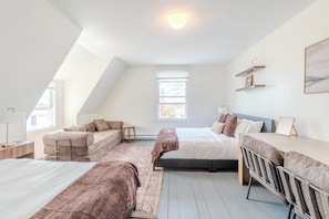 Een slaapkamer met een loft-plafond, een bed, een bank, een bureau en een stoel.