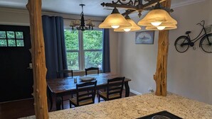 A kitchen with granite countertops, a black stove, and a dining area with a wooden table and chairs. - Cozy Cottage Cabin #1 (Bull Shoals)