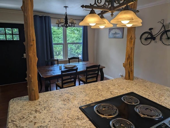 A kitchen with granite countertops, a black stove, and a dining area with a wooden table and chairs.