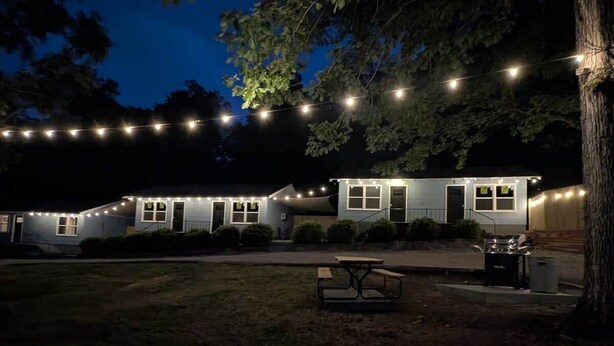 A two-story house with string lights, a picnic table, and a barbecue grill in the yard. - Cozy Cottage Cabin #1 (Bull Shoals)