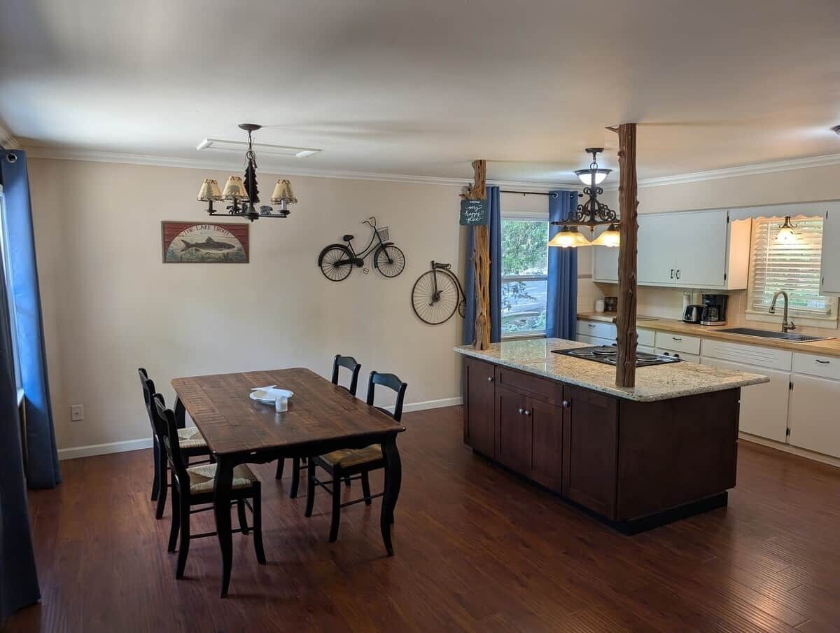 Un coin repas avec une table et des chaises en bois, une cuisine dotée d’un îlot central et un vélo fixé au mur.