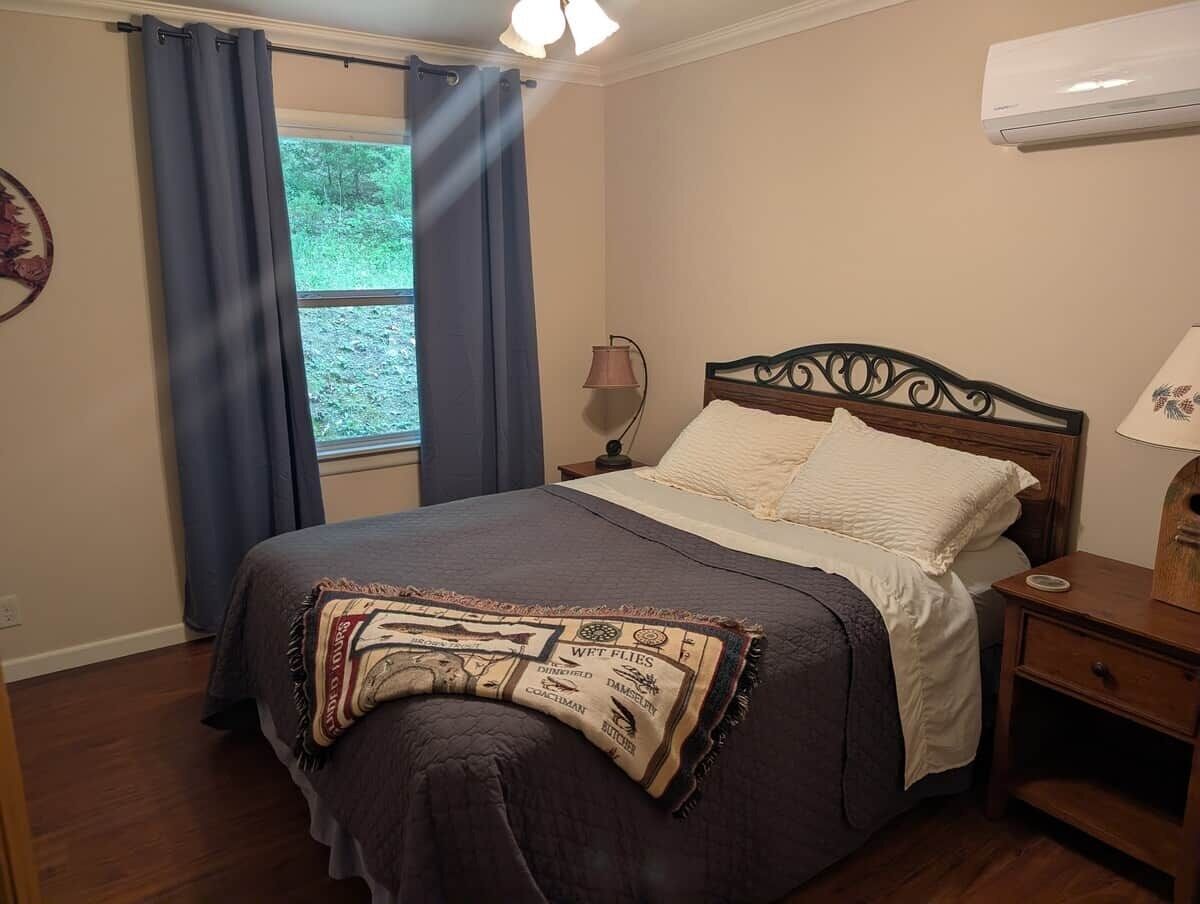 A bedroom with a bed, a nightstand, a lamp, and a window with curtains.