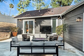 Eine Terrasse mit Gartenmöbeln, Kamin und Fernseher.