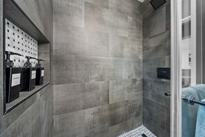 Eine moderne Dusche mit grauen Fliesen, einer Glastür und einem Handtuchhalter mit einem Handtuch.