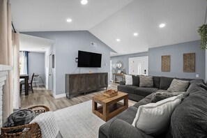 Ein Wohnzimmer mit einer Couch, einem Couchtisch, einem Fernseher und einem Essbereich mit Tisch und Stühlen.