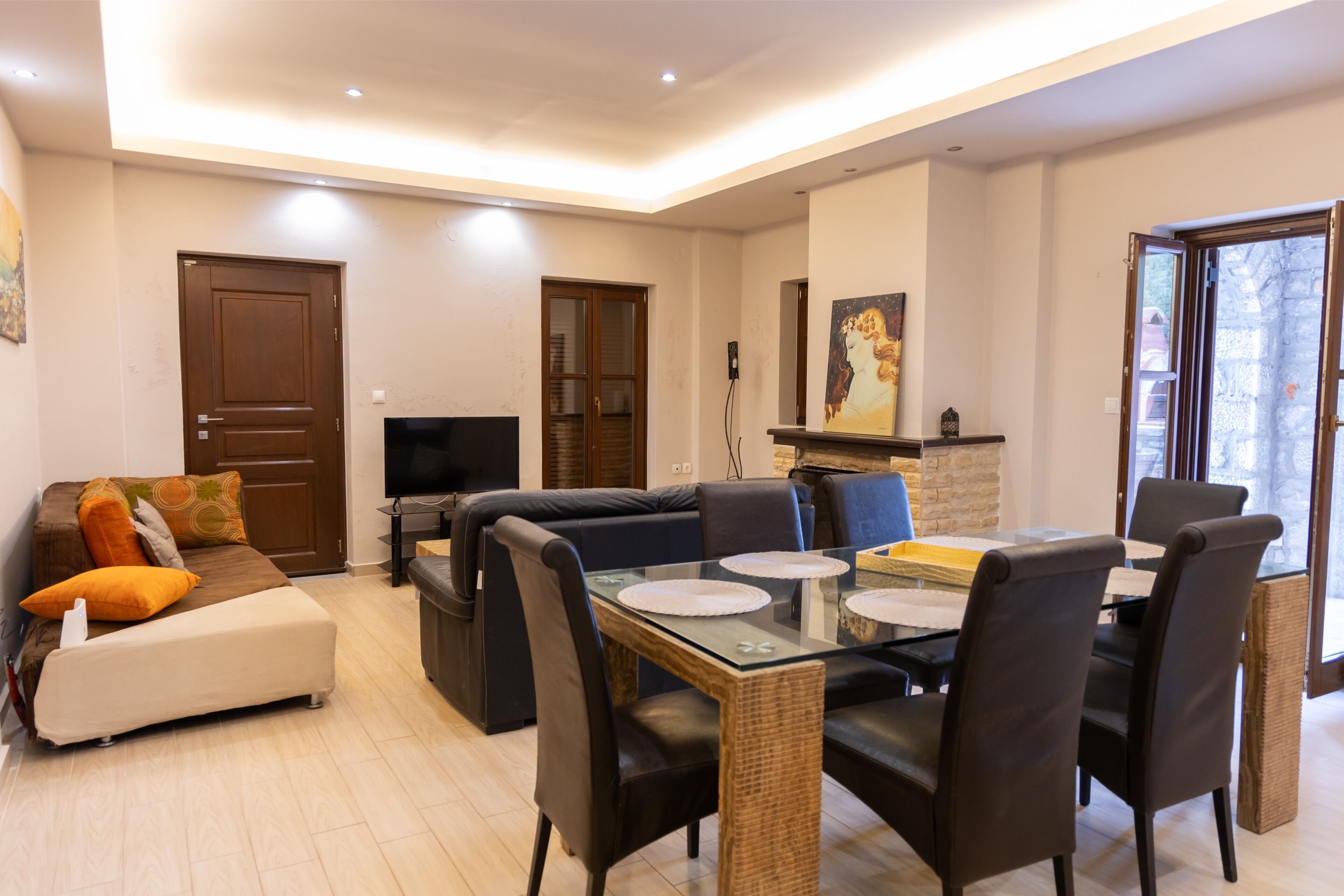 A modern living room with a sofa, TV, dining table, and chairs.