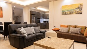 A modern living room with a sofa, a coffee table, and a painting on the wall. - Mani Stone Tower– Sea & Mountain Escape by ΜΡS (Oitylo)