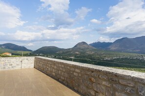 Un balcón de paredes de piedra con vistas a montañas y un cielo despejado.