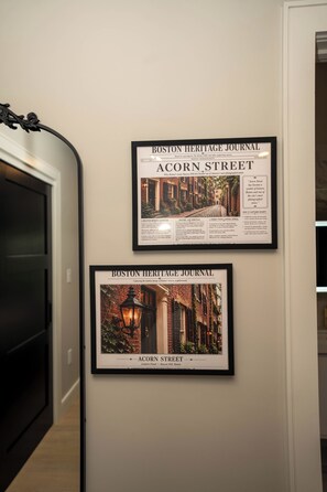 Dos artículos del Boston Heritage Journal enmarcados sobre Acorn Street, colgados en una pared.