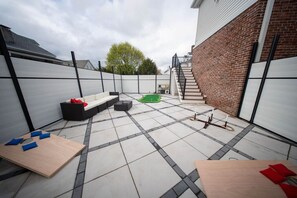 A patio area with a sofa, a small table, and a green play area. - Boston Themed Luxury Stay w Hot tub and Jacuzzi (Medford)