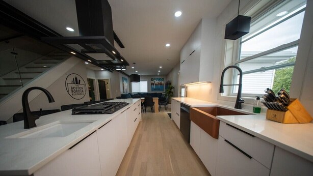 Een moderne keuken met een centraal eiland, een ingebouwde kookplaat en een groot raam voor natuurlijk licht.
