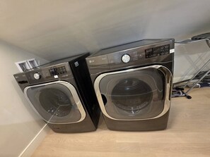 Two stacked front-loading washing machines in a room with a wooden floor and a white wall. - Boston Themed Luxury Stay w Hot tub and Jacuzzi (Medford)