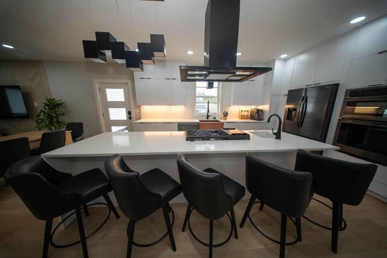 A modern kitchen with a central island, bar stools, and contemporary appliances.