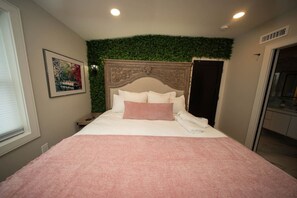 A hotel room with a bed, a headboard with a green wall, a painting on the wall, and a door to the right. - Boston Themed Luxury Stay w Hot tub and Jacuzzi (Medford)