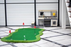 Pienoisgolfkenttä, jossa on kolme rataa, keittiötila ja portaikko.