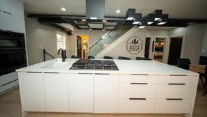 Een moderne keuken met een centraal eiland, een ingebouwde oven en een trap naar een hoger niveau.