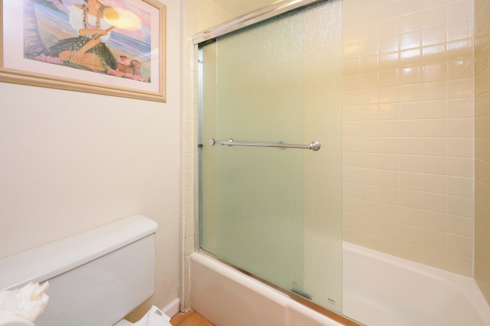 Un baño con ducha, inodoro y un cuadro en la pared.