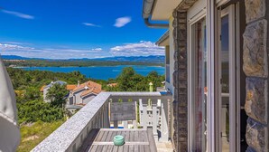 Een balkon met uitzicht op een meer en bergen, een stenen muur en een houten terras.