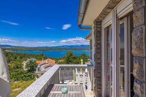 Ein Balkon mit Blick auf einen See und Berge, eine Steinmauer und ein Holzboden.