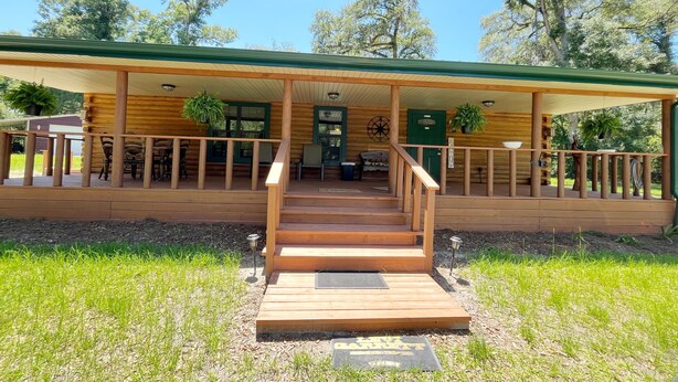 Una cabaña de troncos con un porche, escalones de madera y una puerta verde.
