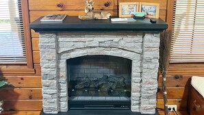Una chimenea con revestimiento de piedra, un televisor montado encima y un letrero sobre el televisor que dice 'LIFE IS GOOD'.