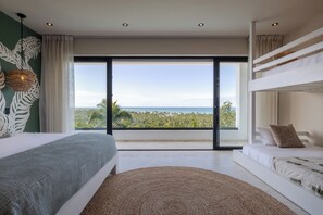 Ein modernes Schlafzimmer mit großem Fenster, Stockbetten und Meerblick.