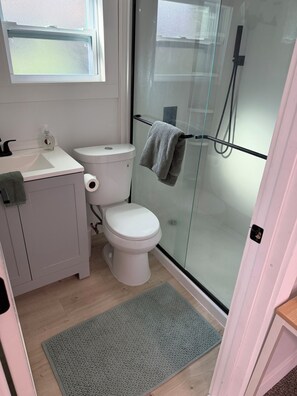 Ein Badezimmer mit Toilette, Waschbecken und einer Duschkabine aus Glas.