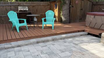 A patio with two Adirondack chairs, a grill, and a small shed.